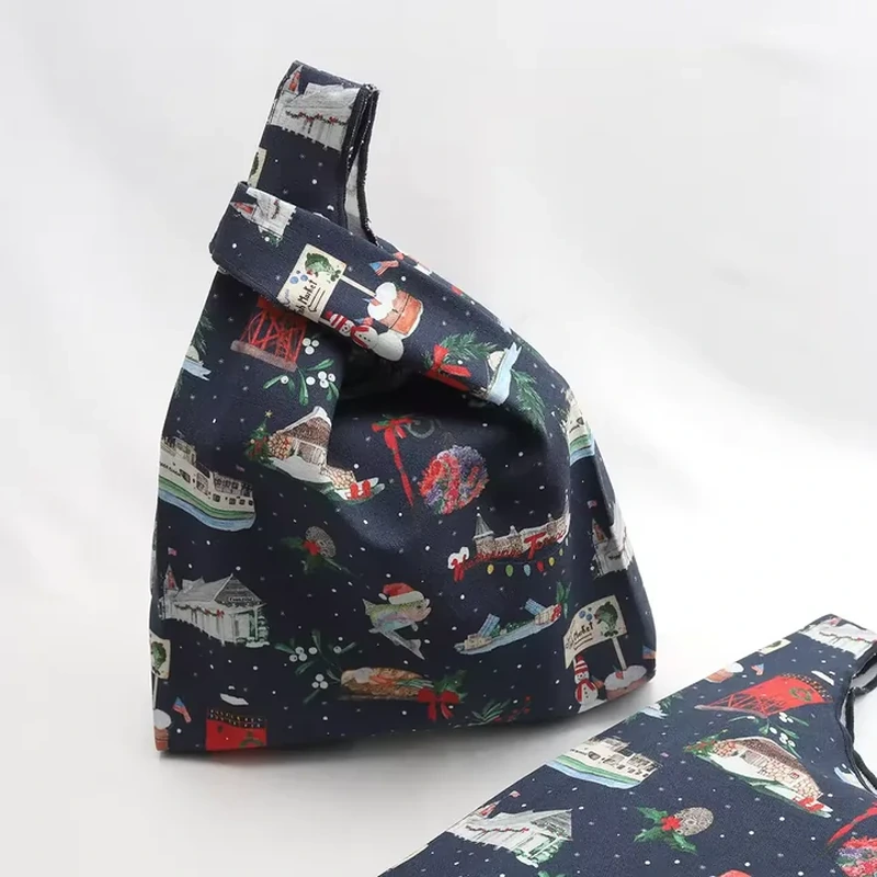 A dark bag has a short knot handle and colorful repeating illustrations across its body