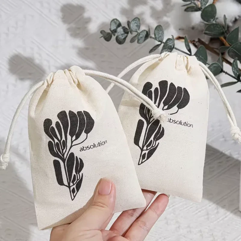 A small pale pouch carries a bold dark botanical silhouette beneath its gathered opening