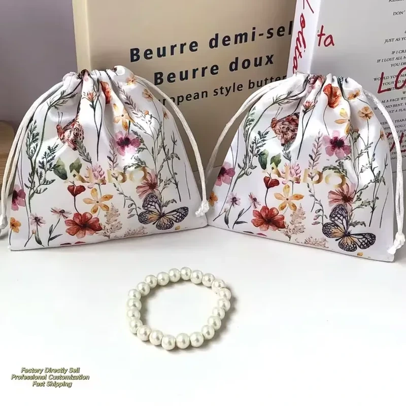 Botanical and butterfly illustrations cover a rounded satin pouch with pale drawstrings