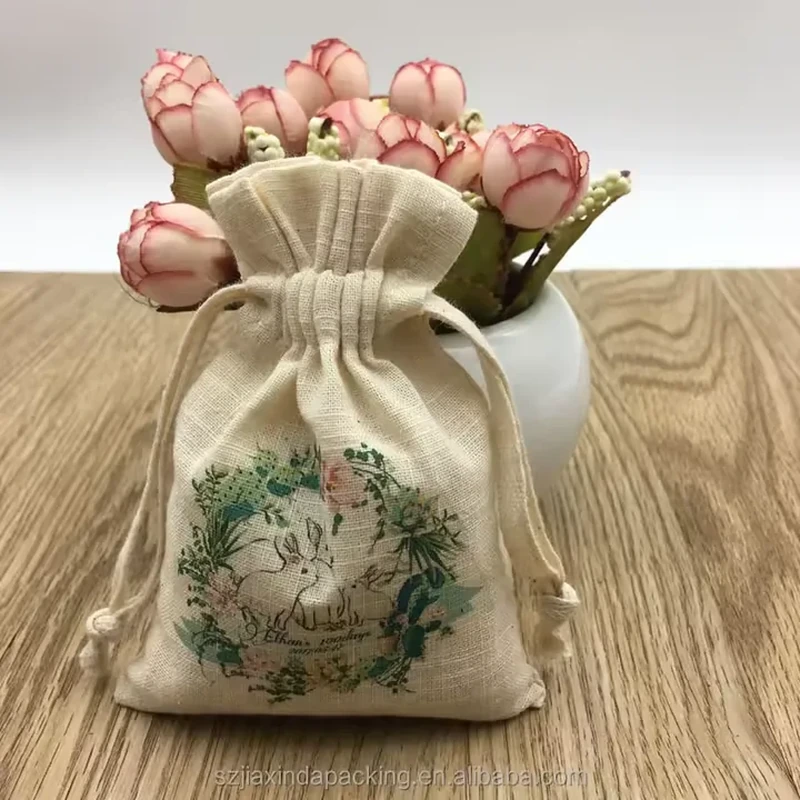 A natural tone pouch has a decorative green botanical wreath beneath its gathered opening
