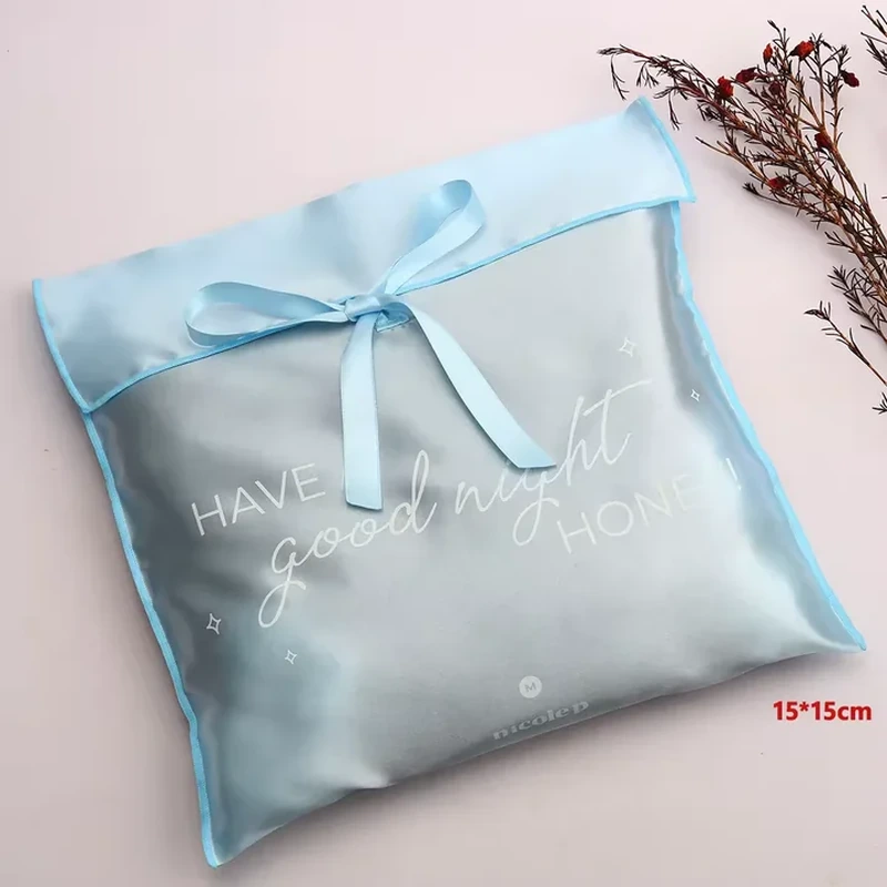 Contrasting edge binding surrounds a square satin pouch with a short flap and matching bow