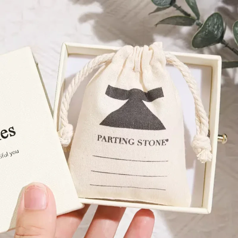 A small pale pouch features a large printed bow beneath its gathered top opening