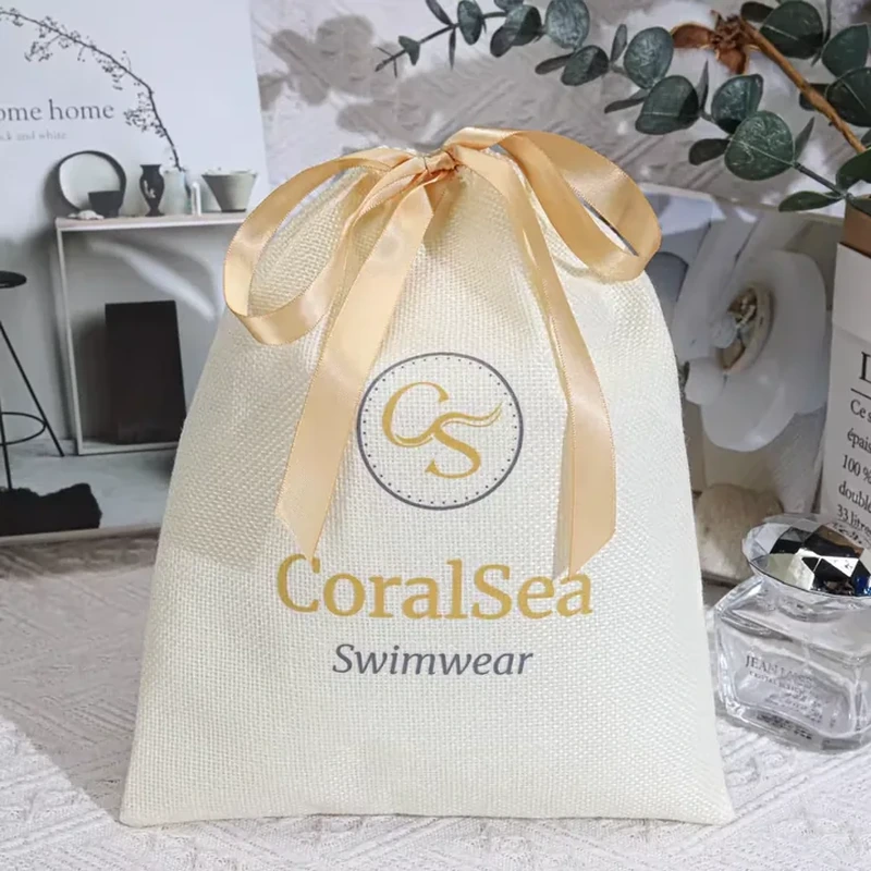 Pale woven apparel gift bag with a large gold ribbon bow
