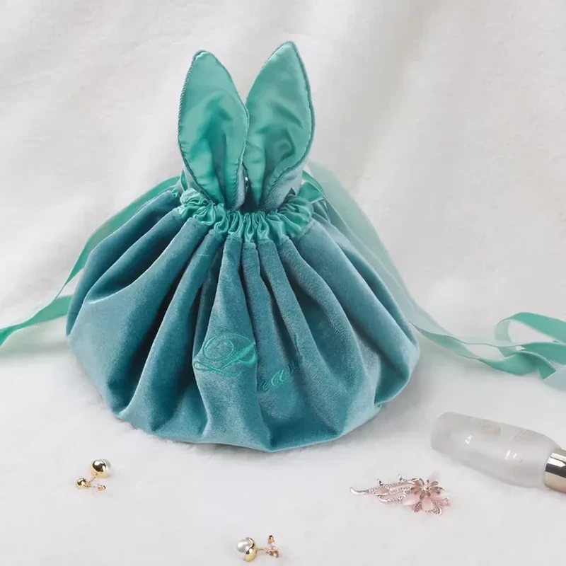 Two upright fabric ears rise above a gathered round pouch with ribbon ties