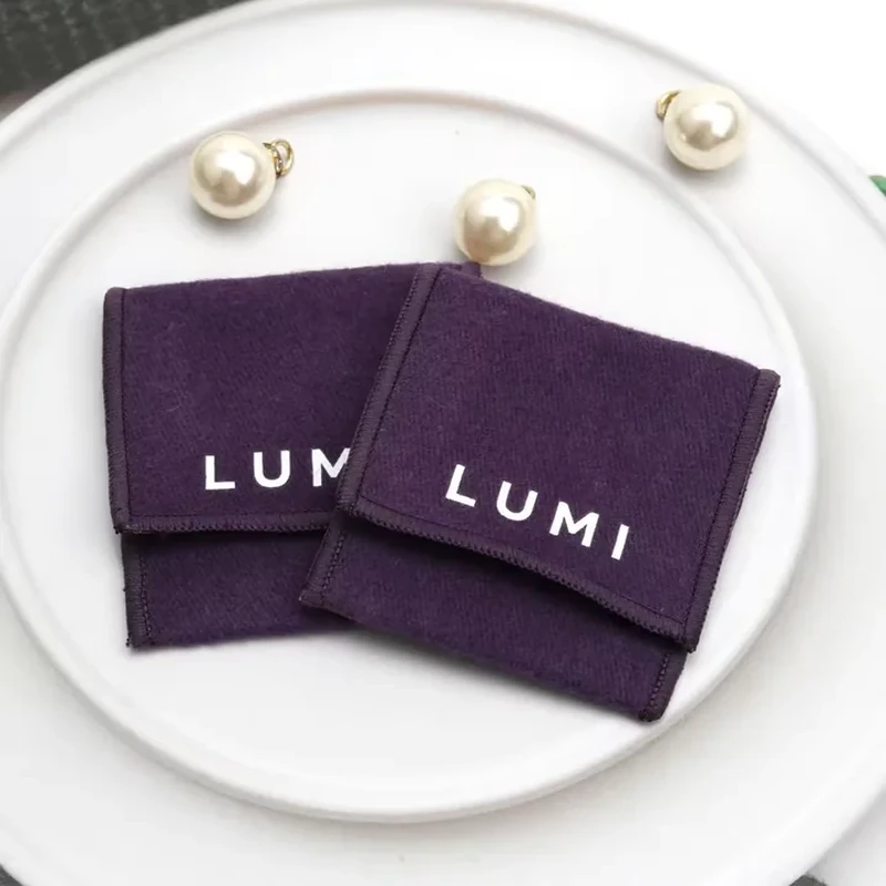 A compact dark pouch uses a square shape, straight foldover edge and centered lettering