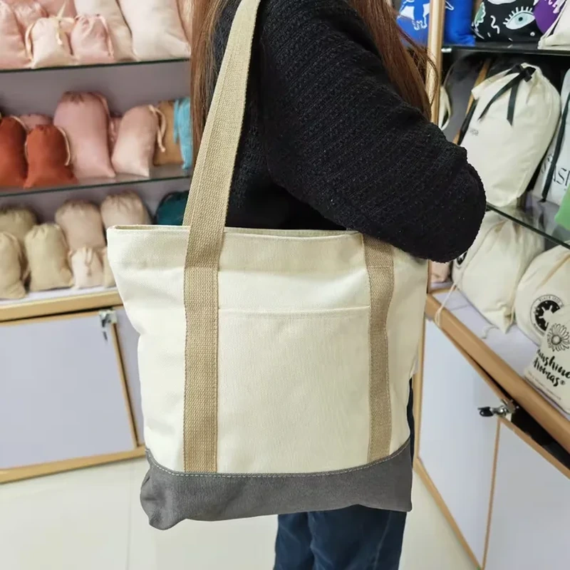 A pale shoulder tote has long handles and a broad dark panel around its lower section