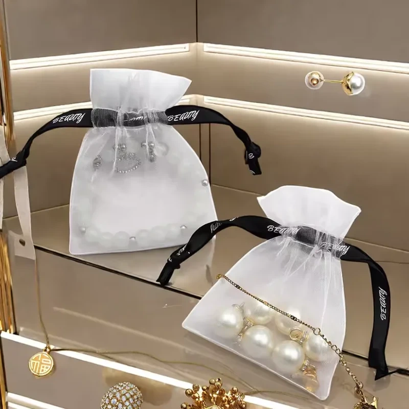 White sheer jewelry bags with black ribbon ties and visible pearl jewelry