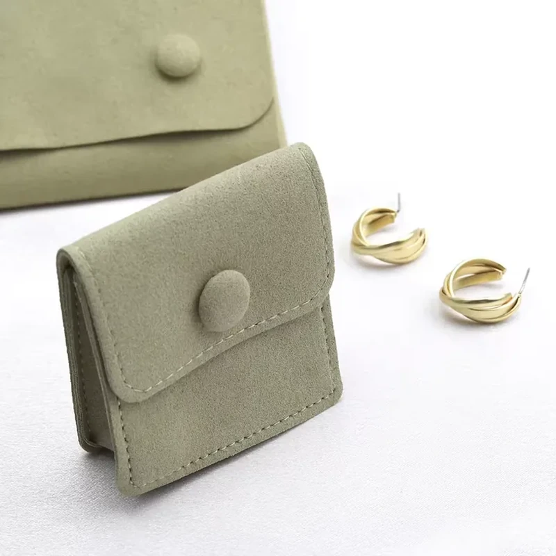 A fabric-covered button secures a short flap on this stitched rectangular jewelry wallet