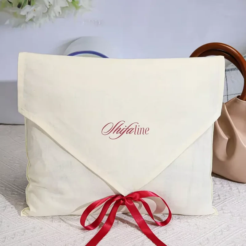A large pale pouch has a deep triangular flap and a contrasting bow at its point