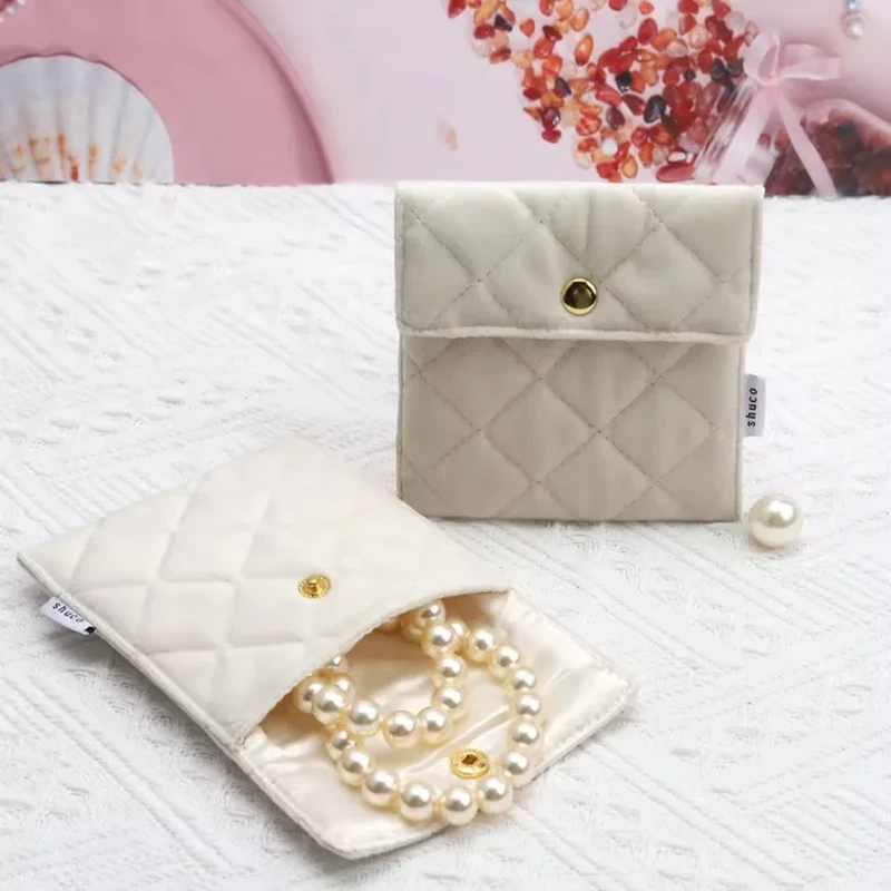 Diamond quilting covers a compact jewelry envelope with a central snap flap