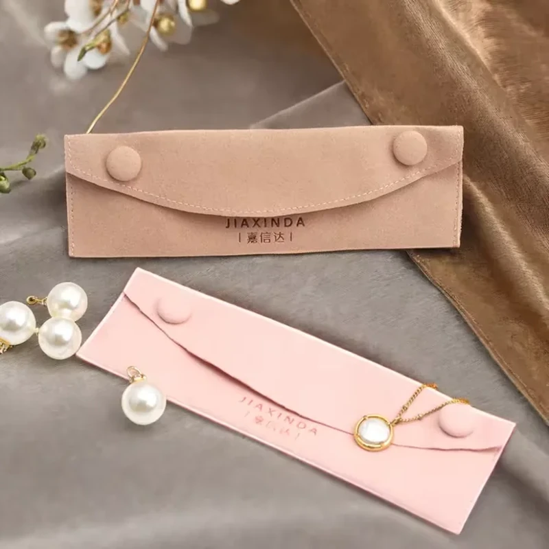 Two covered buttons secure the ends of a slim curved-flap jewelry envelope