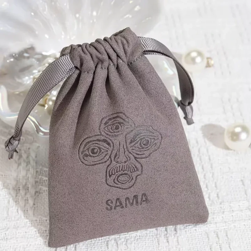 An outlined floral motif is pressed into a gathered pouch with broad ribbon ties