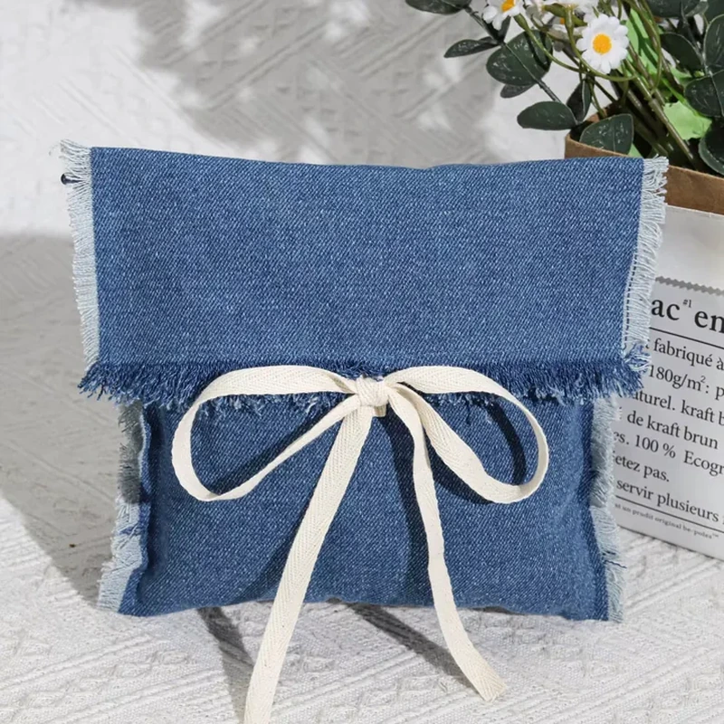 Blue denim-style folded gift envelope with frayed edges and a pale ribbon tie