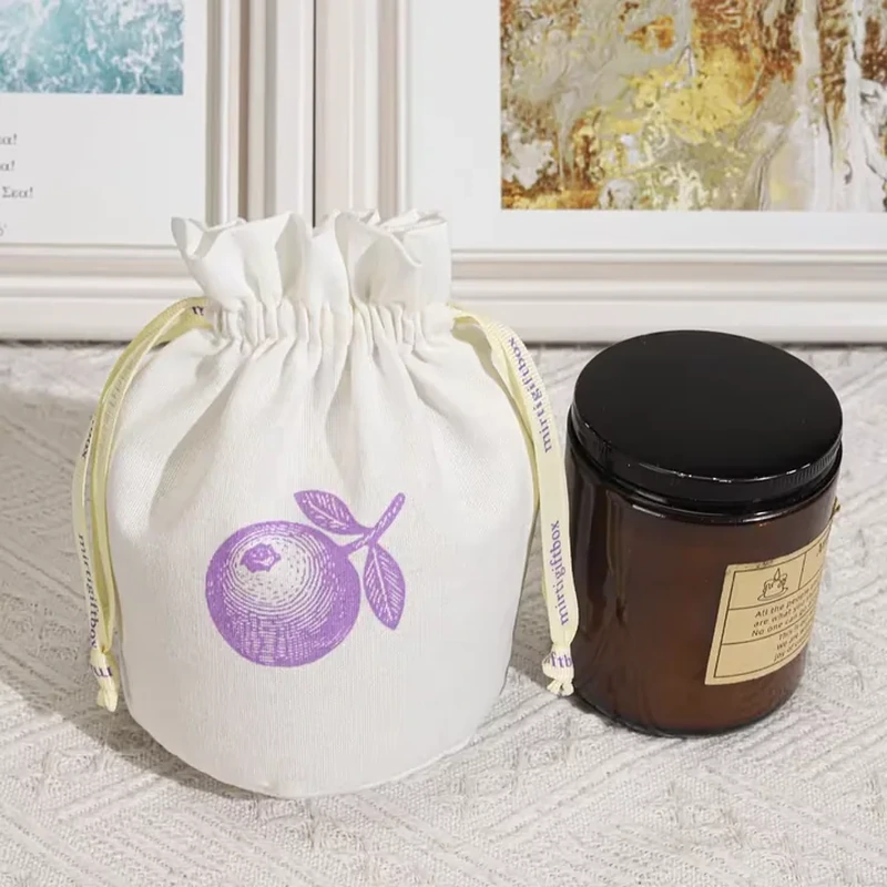 A small round base pouch has a gathered top and a simple purple fruit motif
