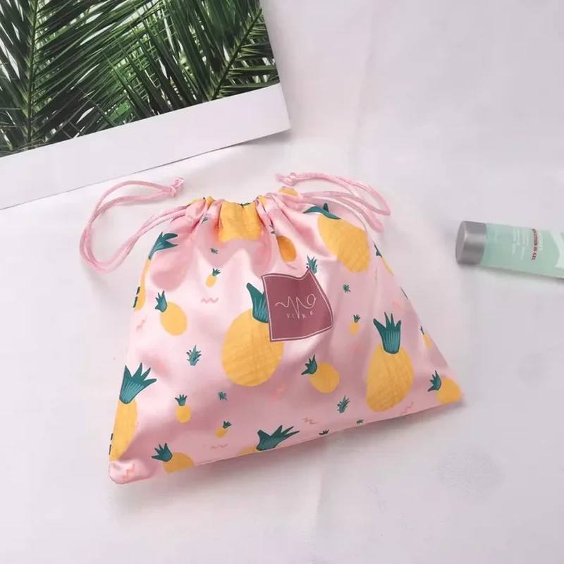 An all-over fruit illustration covers a satin pouch with fine drawstrings and a hanging tag