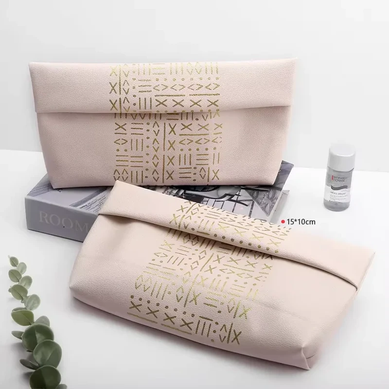 Pale leather-look beauty pouches with broad foldover tops and geometric decoration