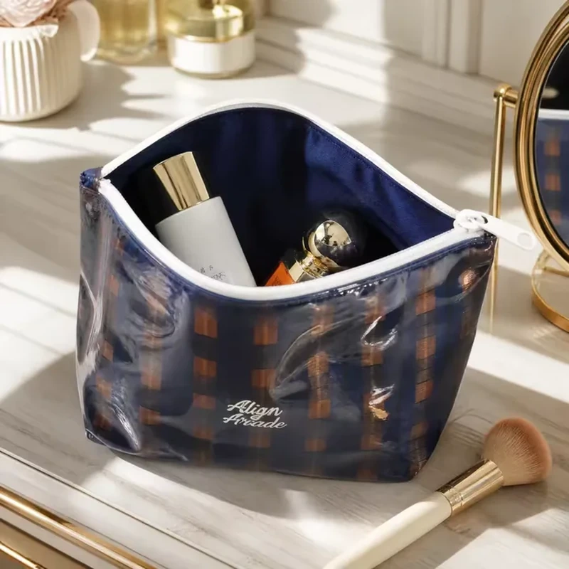 Glossy plaid cosmetic pouch opened wide to show a dark lining and a light zipper rim
