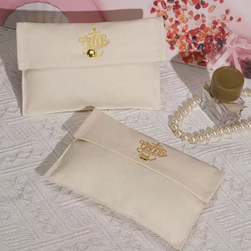 A pale flat pouch uses a straight folded flap and a small gold tone central button
