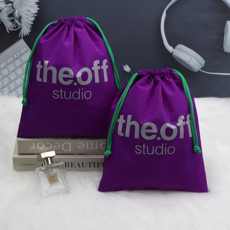 Purple drawstring pouches with a visible square-grid fabric texture and bright green cords