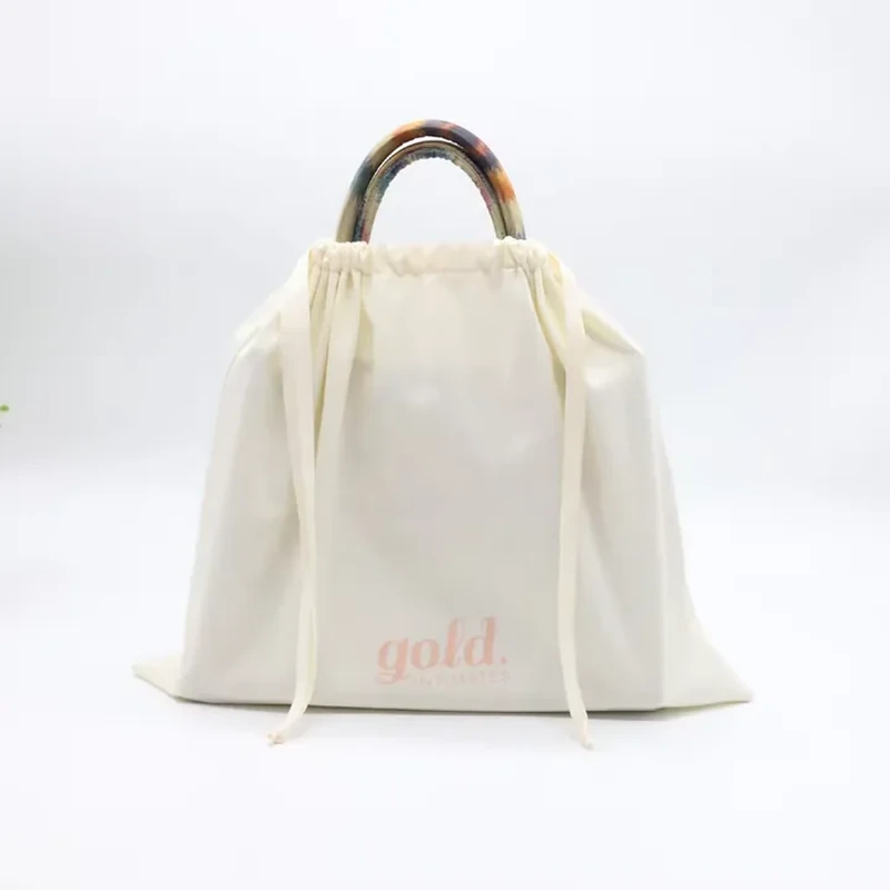 A roomy pale cover gathers around a handbag while leaving its carrying handles visible
