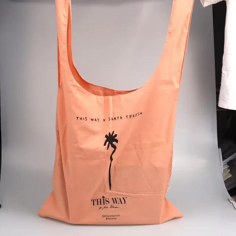 A narrow tote combines an extended handle opening with a small centered palm tree graphic
