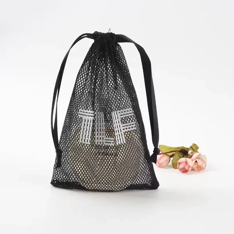 Black diamond-mesh drawstring bag with long flat ribbon loops and a visible round container