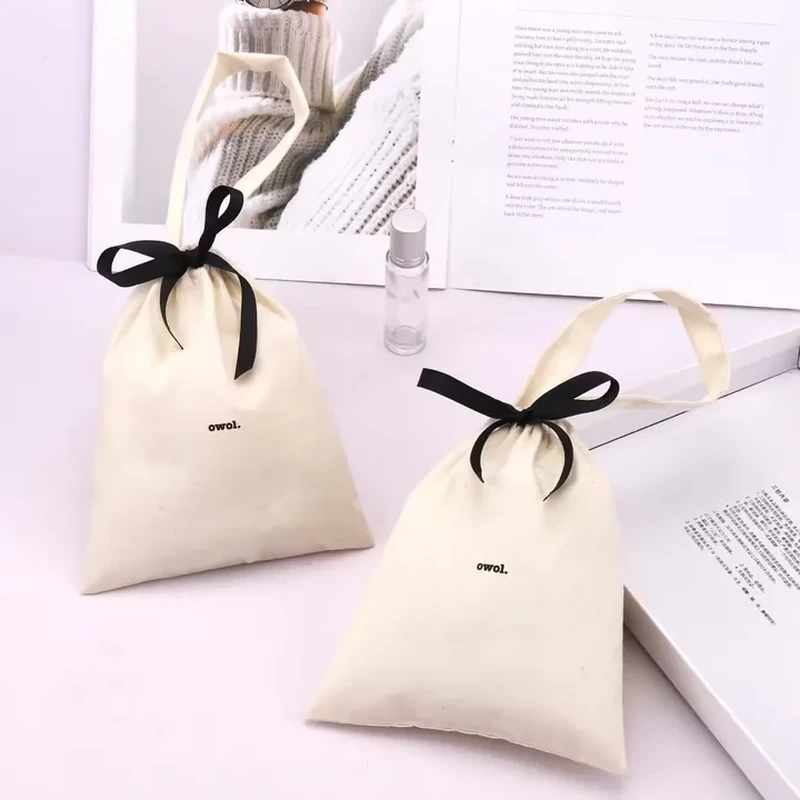 A small gathered pouch has long contrasting ribbons tied into a bow above its narrow neck