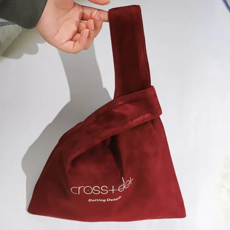 An elongated fabric loop threads through a shorter opening to close this soft bag