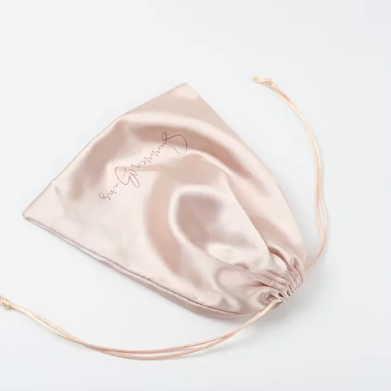 Blush pink satin pouch with a gathered opening and thin drawstrings.