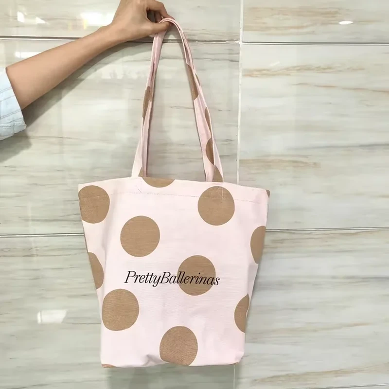 A pale tote displays large scattered dots and two long matching fabric handles