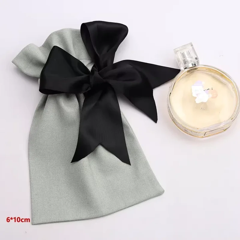 A pale gathered pouch carries an oversized dark bow that wraps around its narrow neck