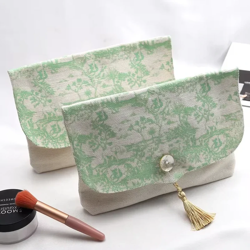A small flap pouch features a delicate green pattern and a decorative hanging tassel