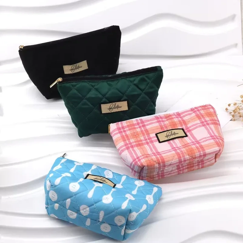 Four zipper pouches in plain, quilted, plaid and illustrated designs, each with a front label.