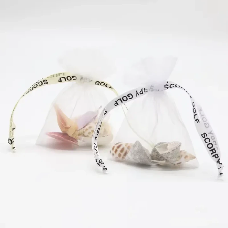 White sheer favor bags with printed ribbon drawstrings and visible contents