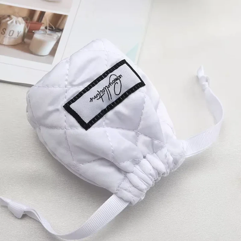 A pale drawstring pouch has quilted stitching, a soft gathered top and a small framed label