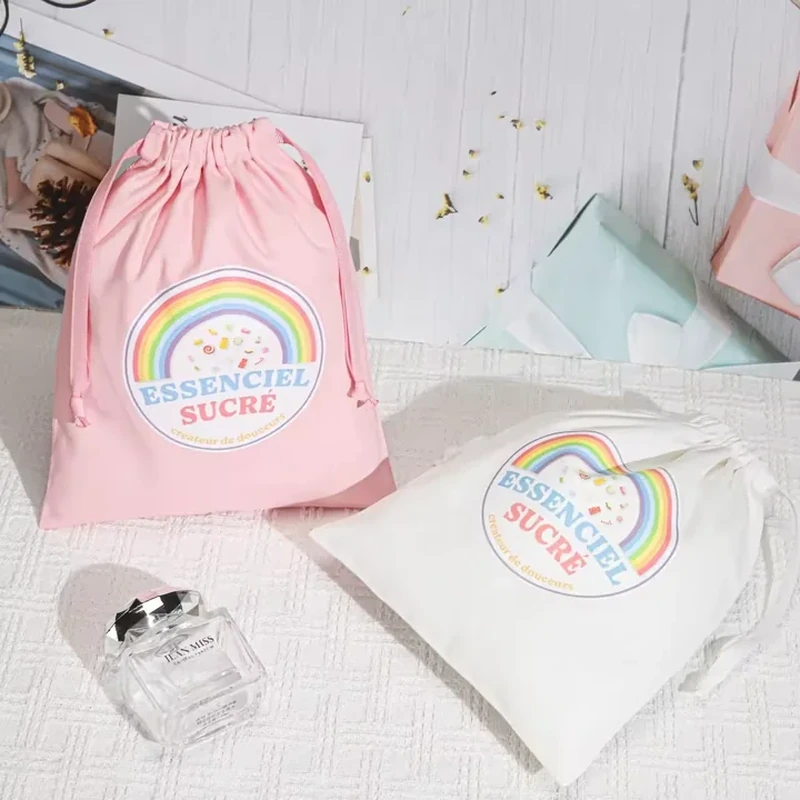 A drawstring pouch features a colorful rainbow badge and short centered lettering on the front