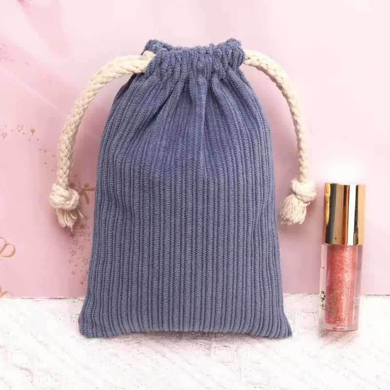 Vertical ribs and thick rope drawstrings give this tall rectangular pouch a tactile finish