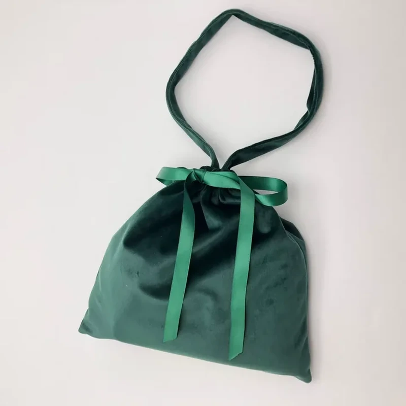 A soft rectangular pouch combines a fabric loop handle with a front ribbon bow