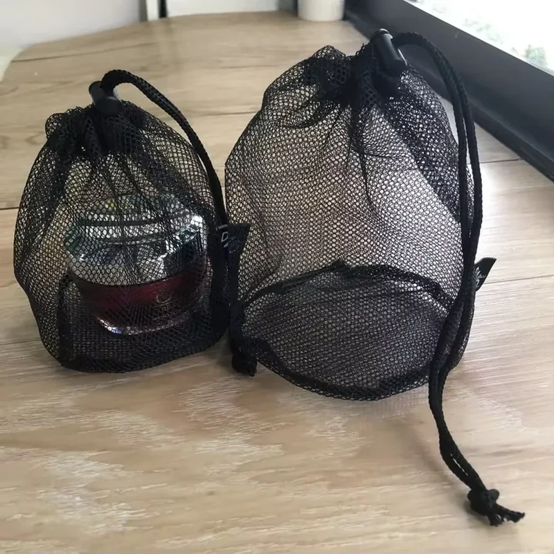 Black open-mesh drawstring pouches with circular bases around bottle-shaped contents