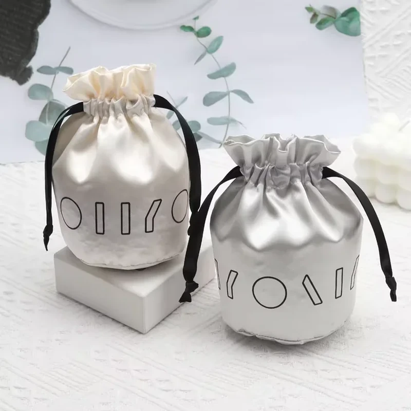A rounded base and short ruffled neck create a compact satin pouch with contrasting ties