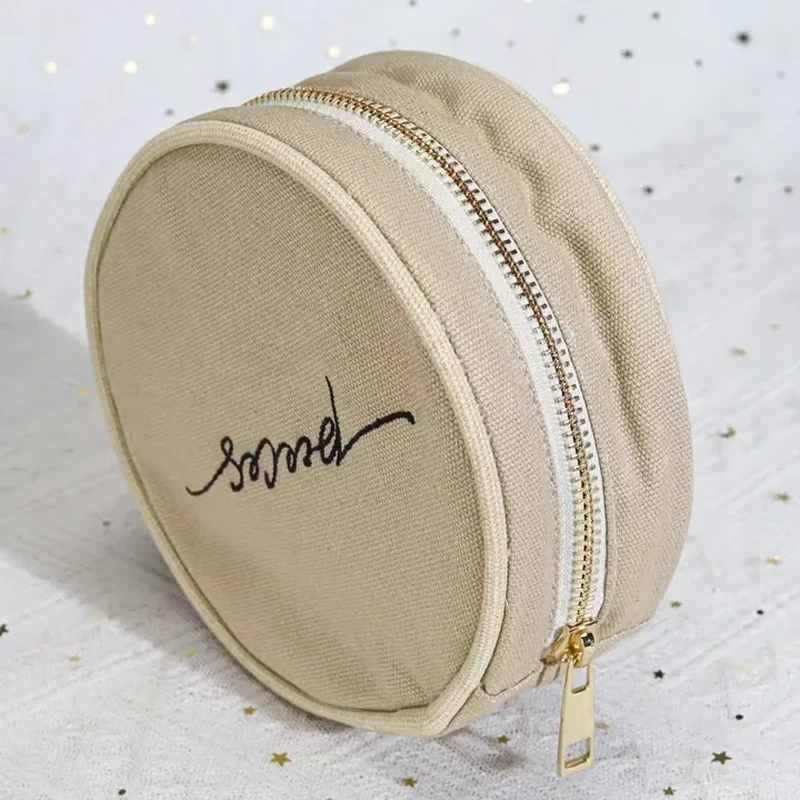 A small circular case has an all around zipper and a compact rounded profile