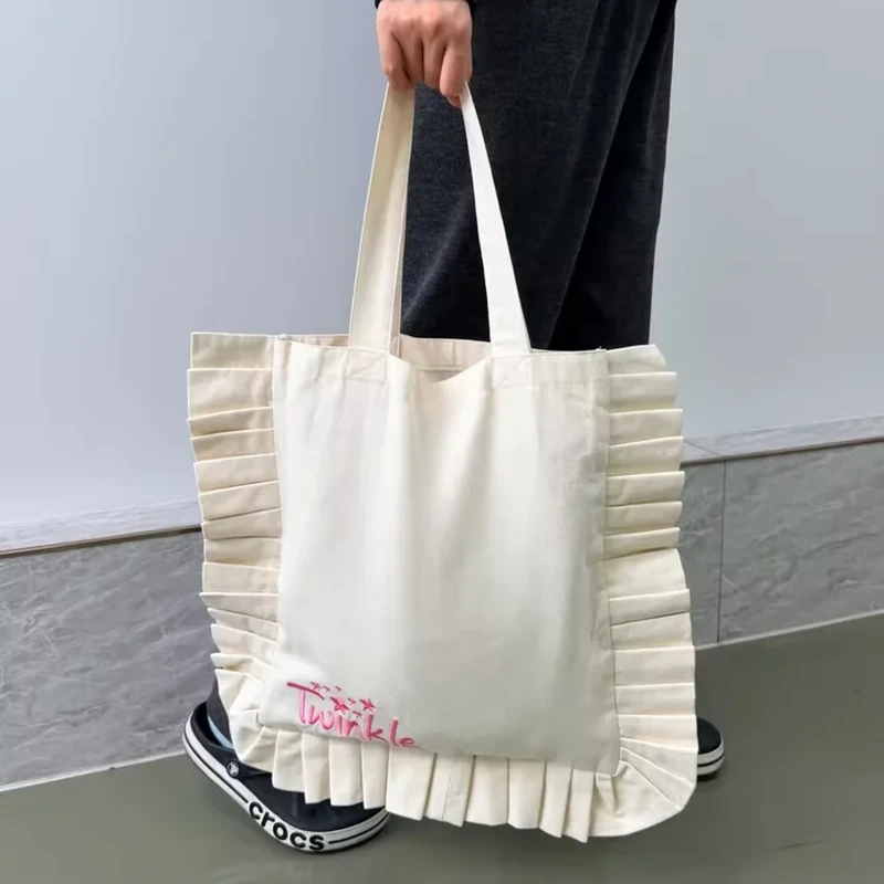 A pale shoulder tote has a ruffled border running around its sides and lower edge