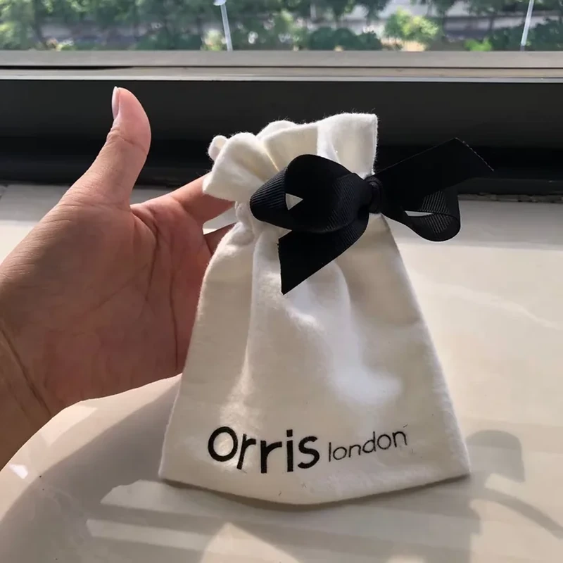 A small ivory pouch features a ruffled upper edge and an oversized dark bow