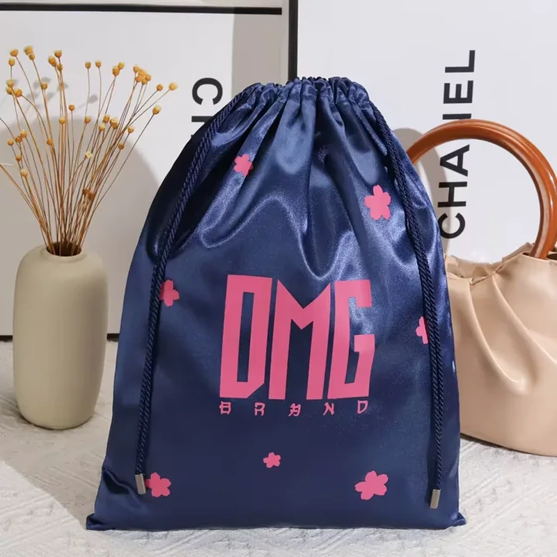 Scattered flower motifs surround bold central lettering on a tall satin drawstring bag