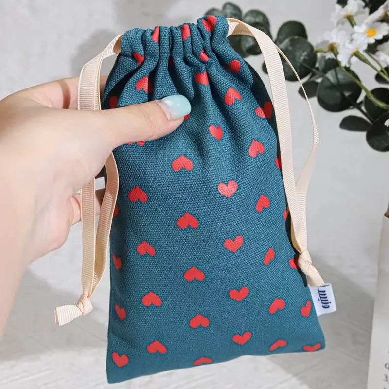 A narrow dark pouch shows small scattered red hearts beneath a gathered top