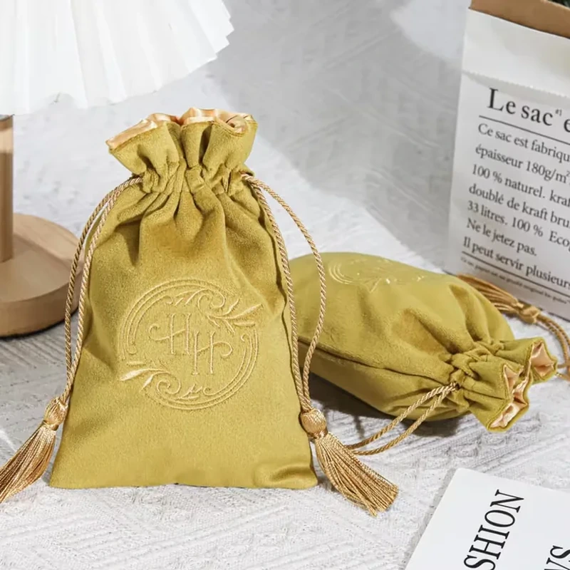 Two tassel-ended drawstrings and a ruffled top frame this short rectangular pouch