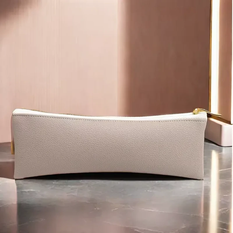 Long pale leather-look zipper case with tapered lower profile and gold-colored pull