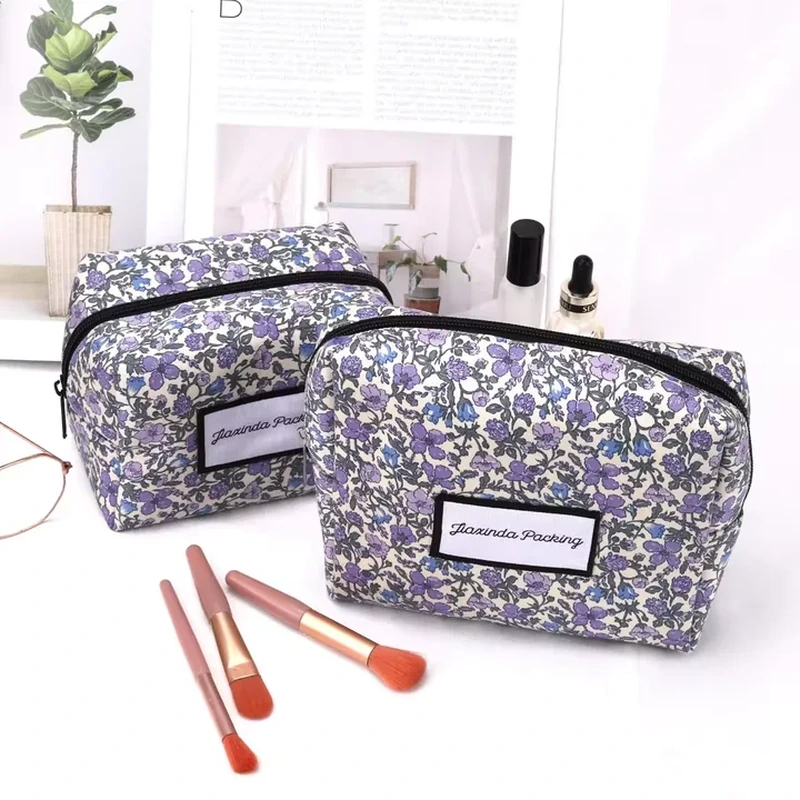 A compact rectangular cosmetic bag features an allover small floral print and dark zipper edging