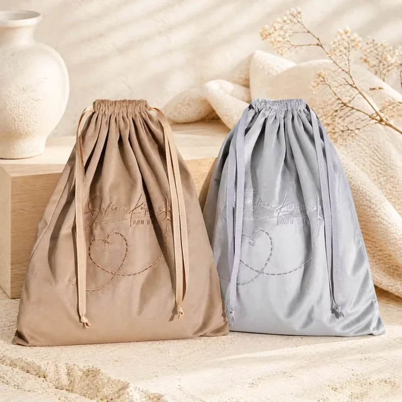 A broad soft-sided sack gathers under long drawstrings and displays a large front motif
