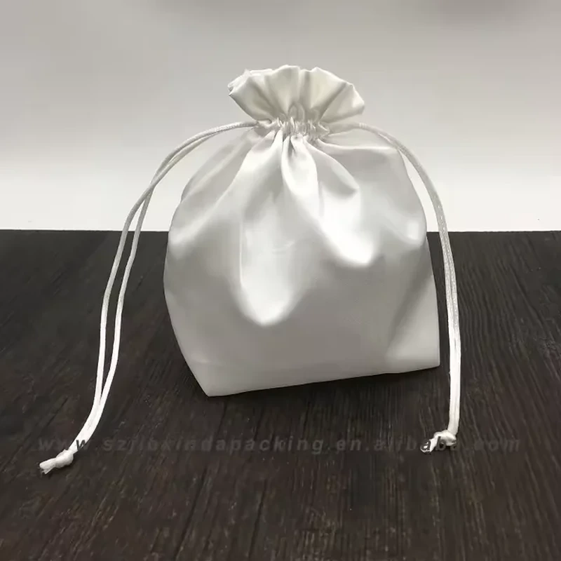 A defined square base supports an upright satin pouch with a high gathered neck